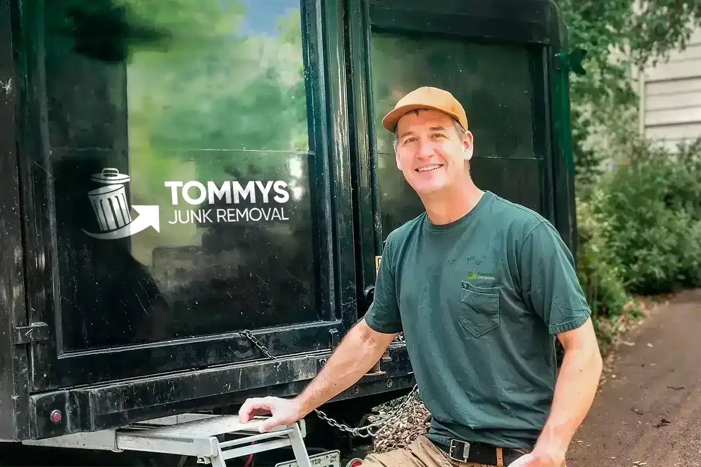 A smiling Tommy's Junk Removal employee standing behind a truck ready to haul away junk, in Fort Myers,FL.