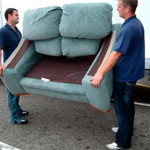 Two employees of Tommy's Junk Removal carrying a sofa during a furniture junk removal service.